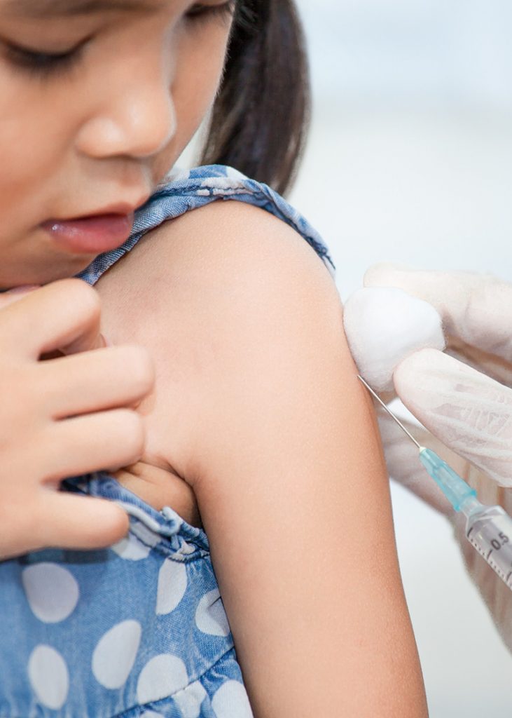 Doctor injecting vaccination in arm of young asian girl