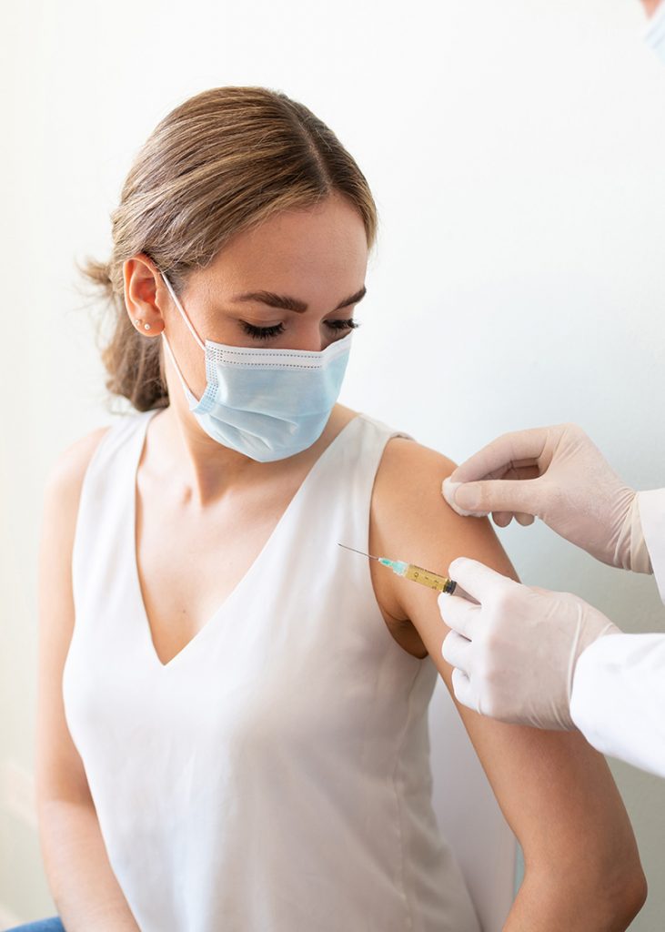 Doctor using a cotton swab with alcohol to clean a woman's arm before applying a vaccine in a doctor's office