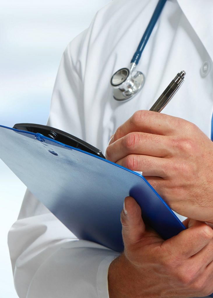 Doctor with stethoscope around his neck holding pen to a medical chart on a clipboard.