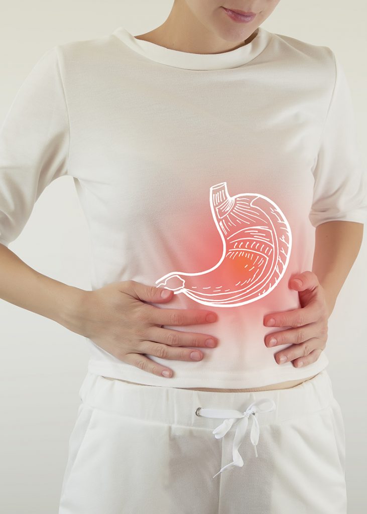 Digital illustration of inflamed stomach depicted by woman holding her abdomen and red glowing light around illustration to indicate pain.